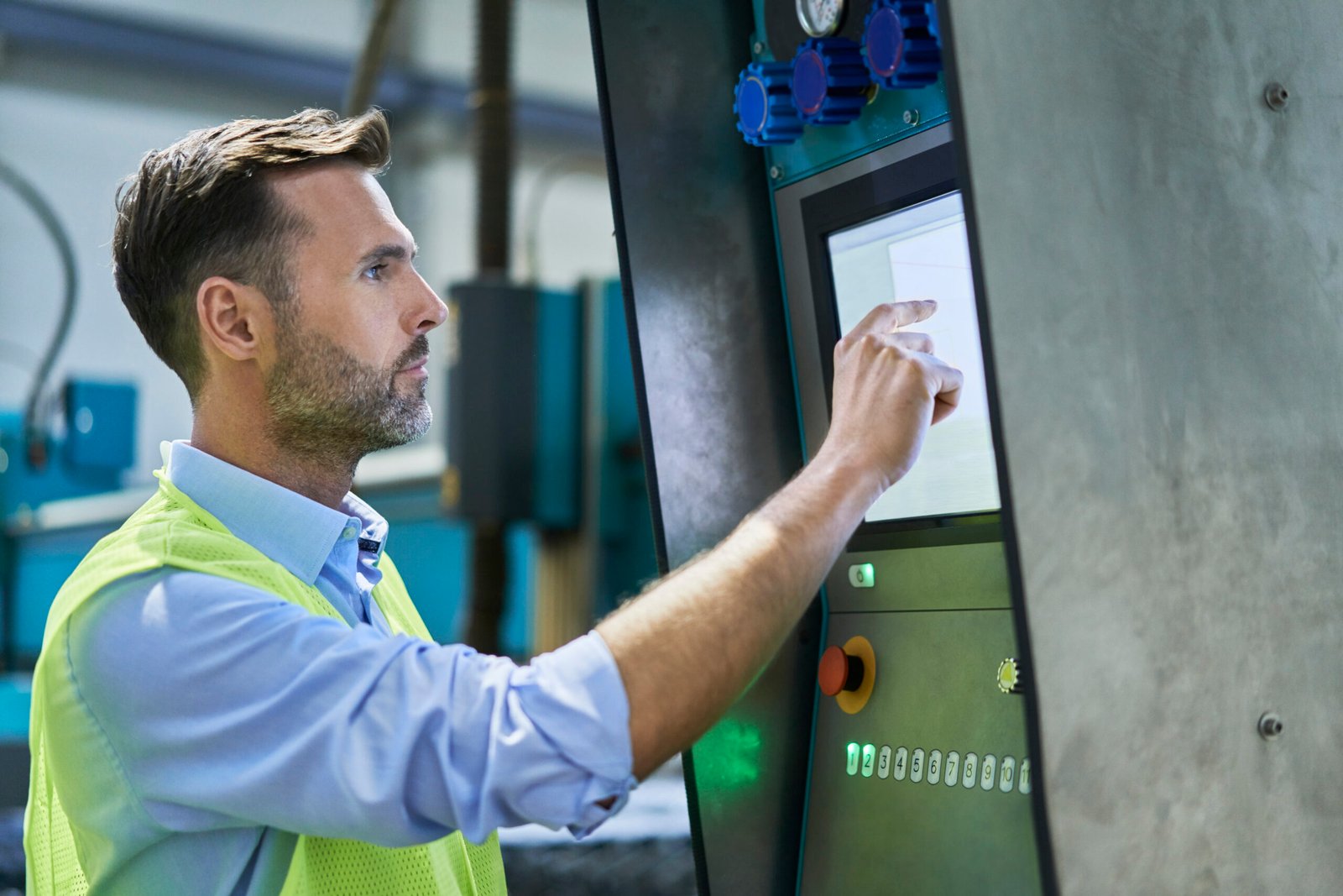 Engineer using computer and operating machinery in factory